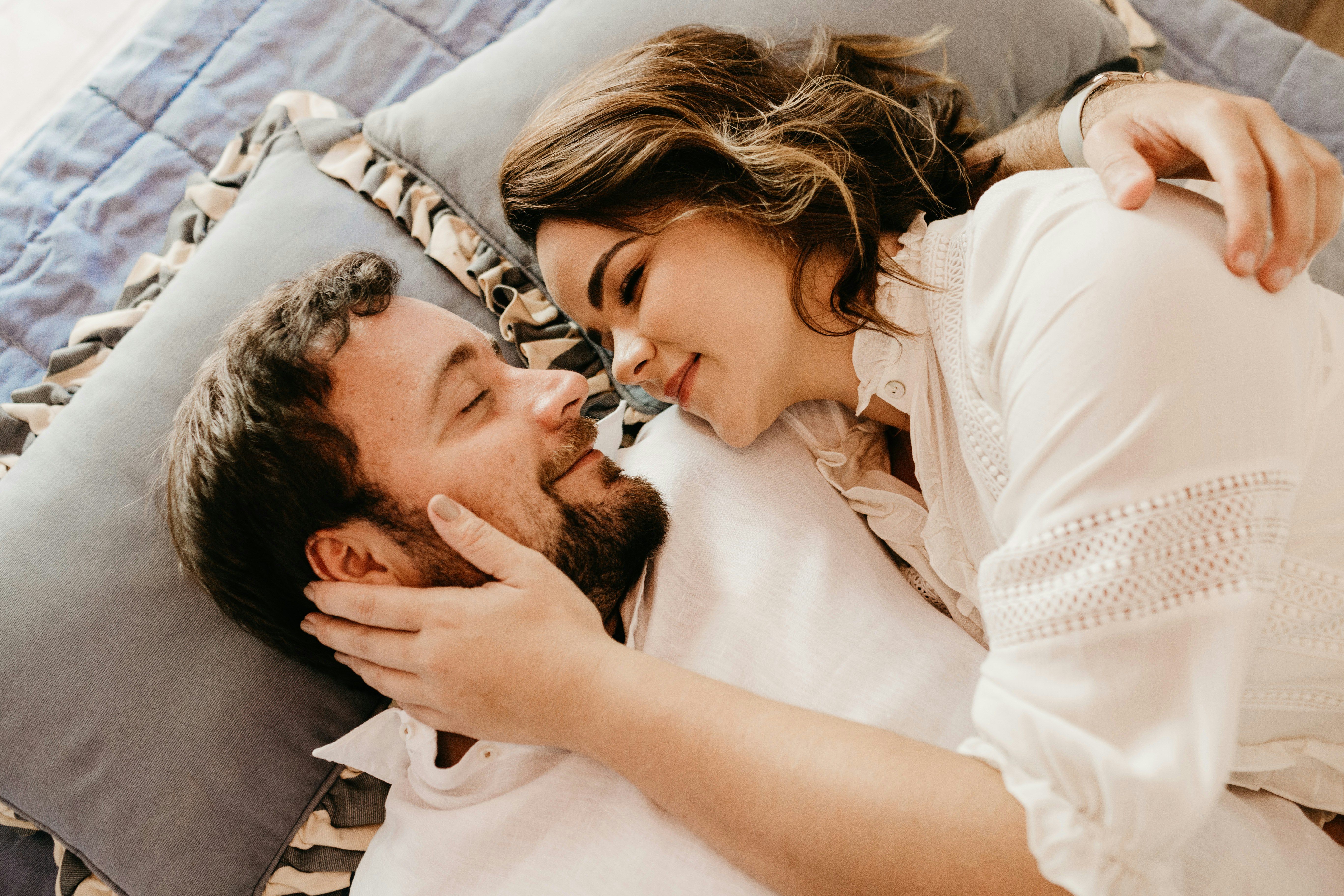 man in white shirt lying on bed beside woman in white shirt